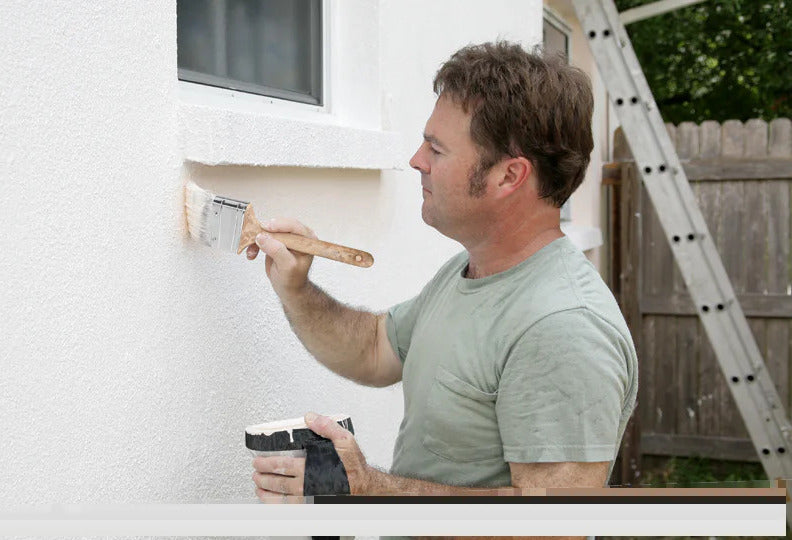 Mann streicht Aussenwand mit Kalkfarbe