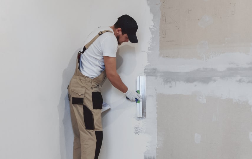 Malermeister verspachtelt eine große Wand