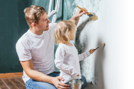 Mann streicht Wand mit seiner Tochter