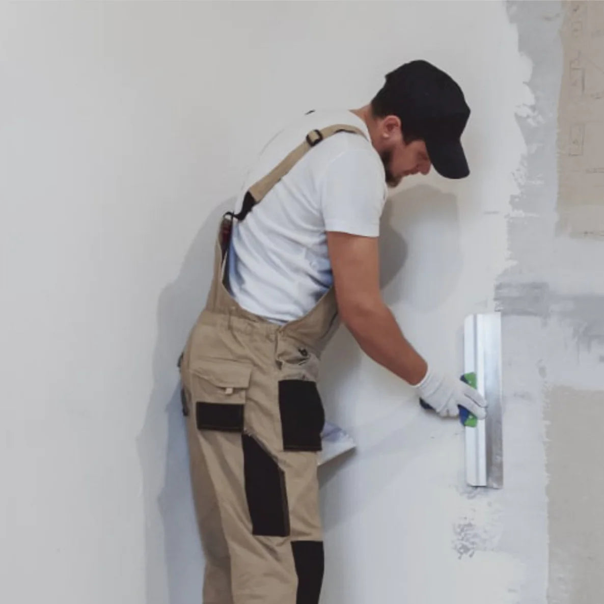 Handwerker traegt Fertigspachtel mit einem Flaechenspachtel auf