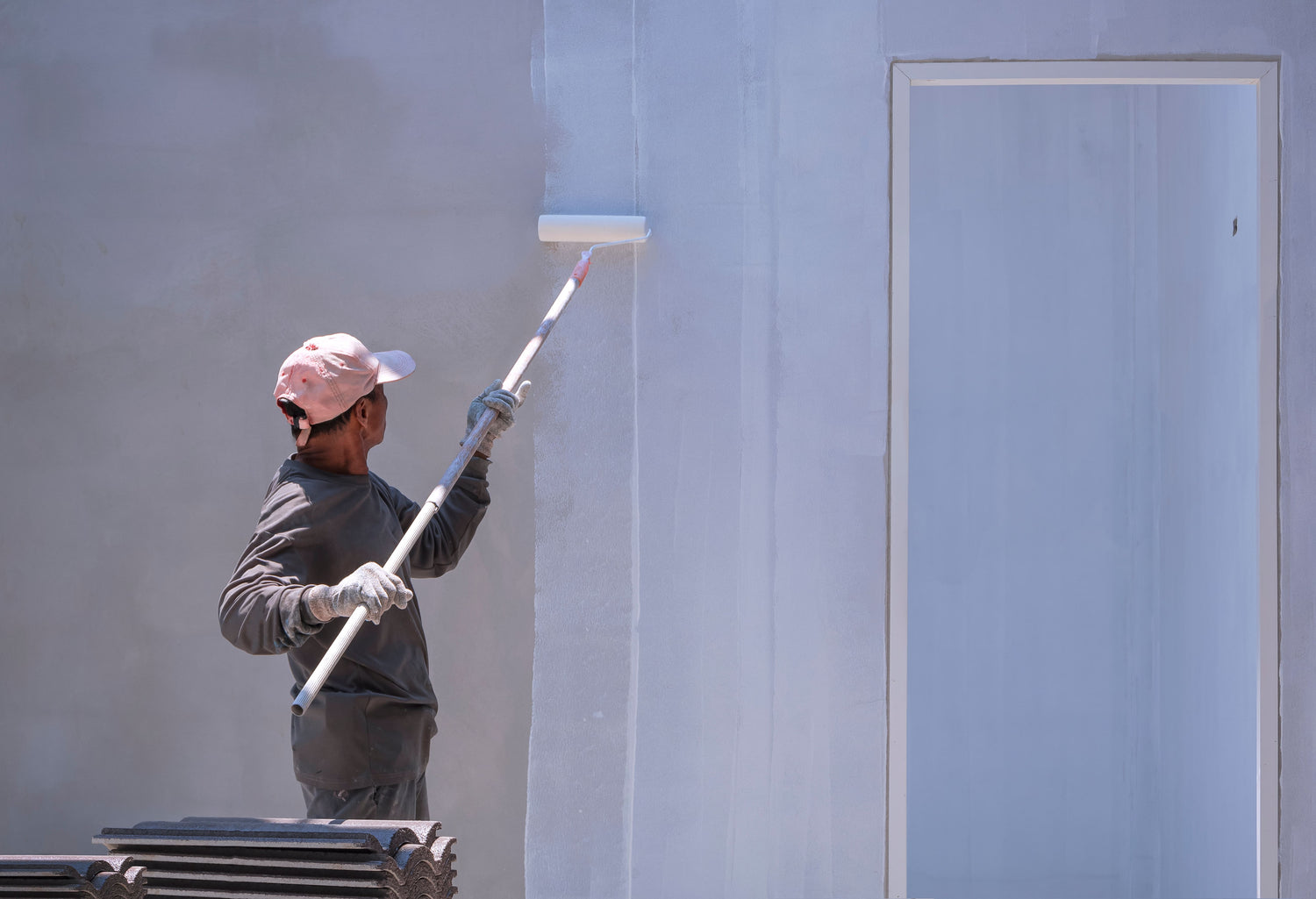 Maler streicht Fassade mit Farbroller