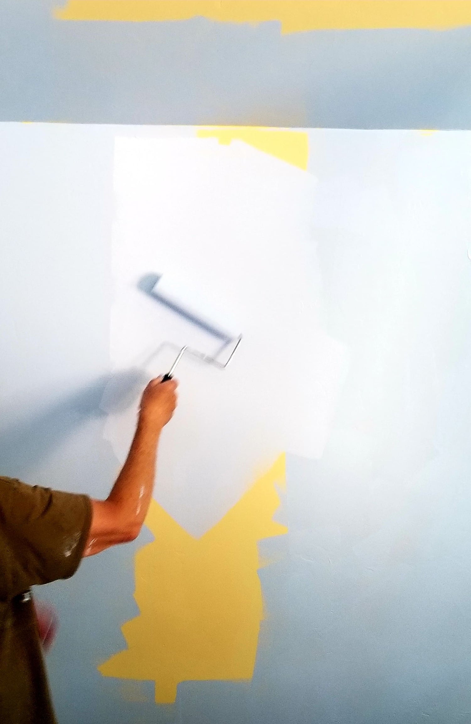 Maler streicht Wand mit Farbroller